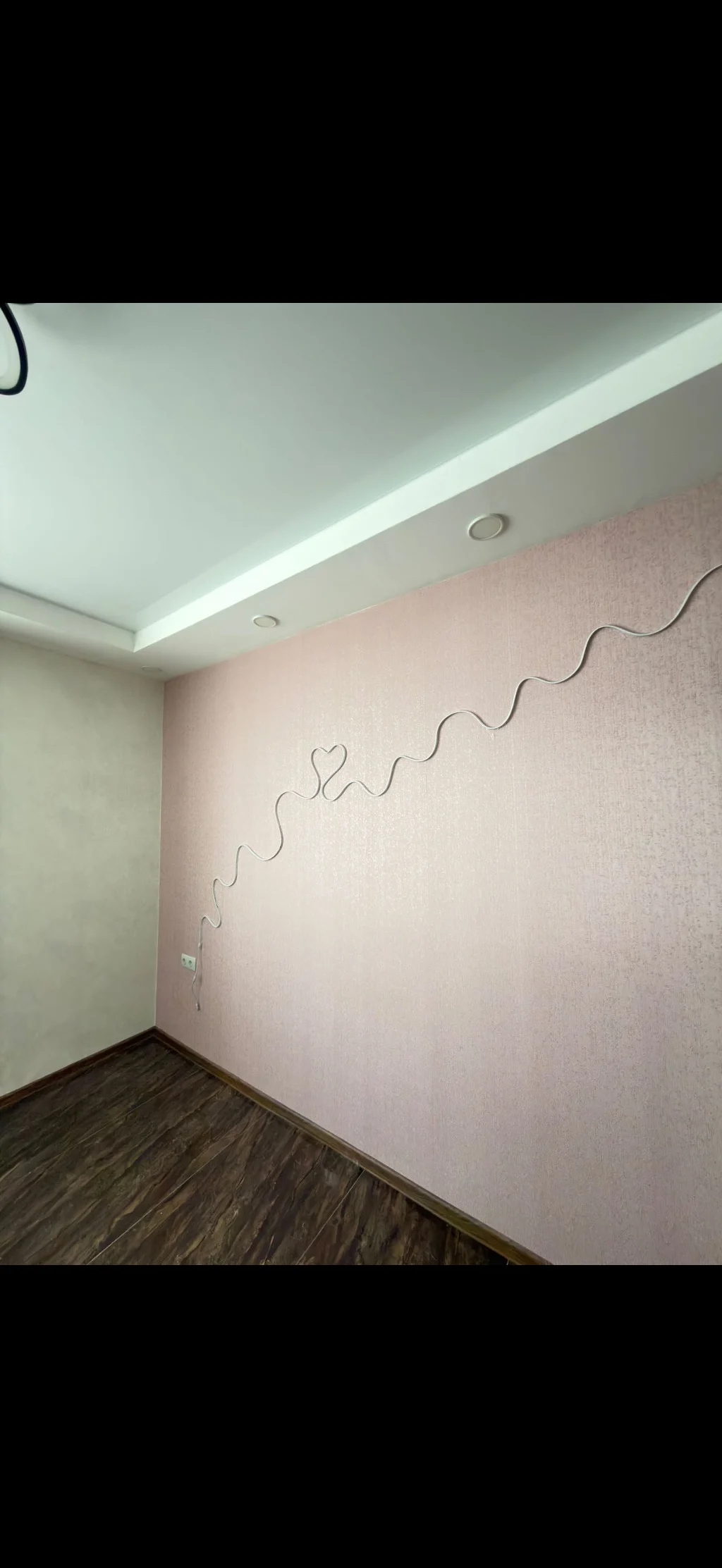 A soft pink accent wall with a unique wavy wall decoration.