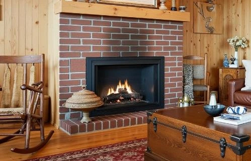 Black rectangular fireplace set in a red brick wall adds warmth and character to a small living room.