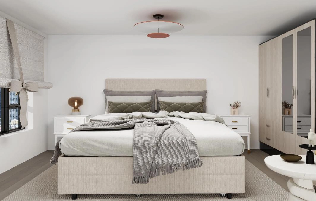 Layered gray pillows arranged on the bed in a small studio apartment.