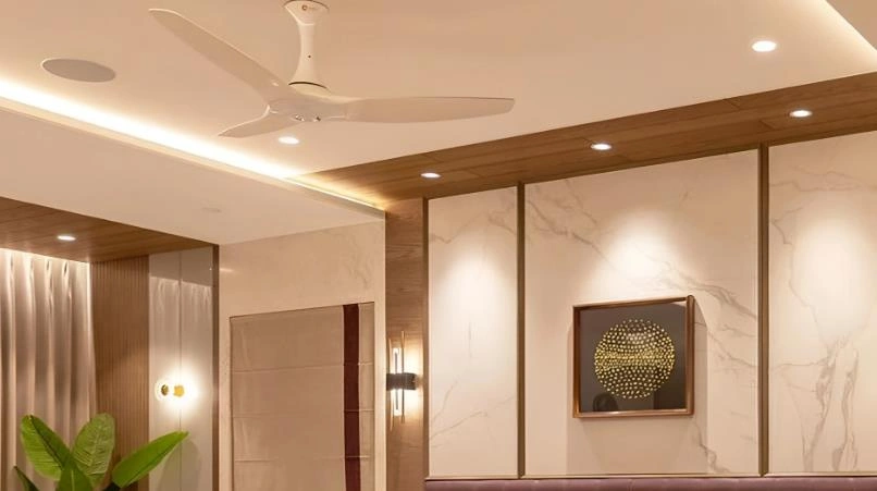 White ceiling fan with POP false ceiling in a modern master bedroom.
