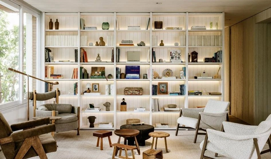 Floor-to-ceiling open white shelving unit in a small living room.
