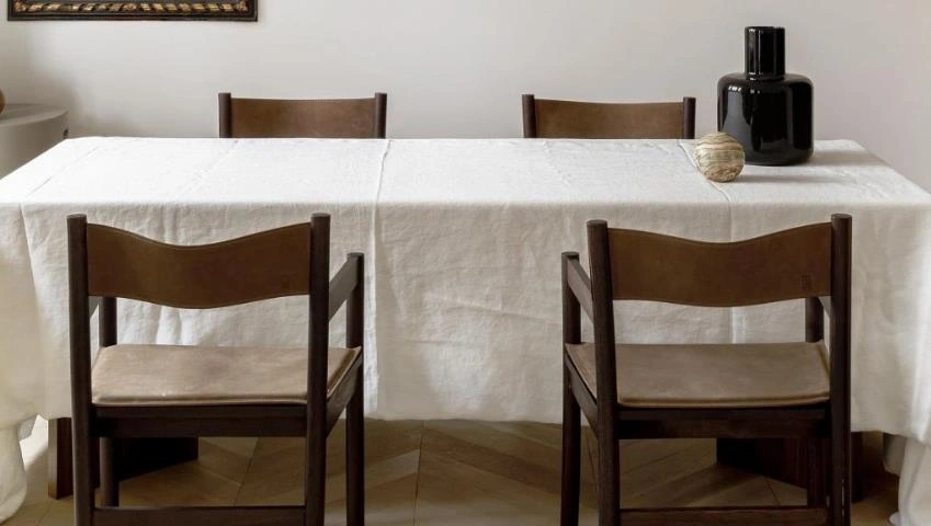 White linen tablecloth covering the dining table in a small apartment dining room.