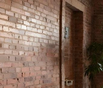Rustic exposed red brick walls in a tiny apartment living room.