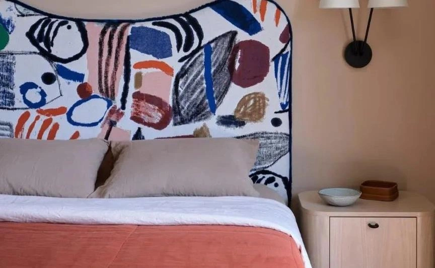 Colorful abstract headboard design in a small apartment bedroom.