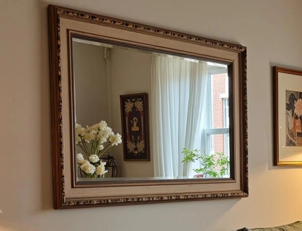 Large decorative mirror with carved frame hanging in a small bedroom.