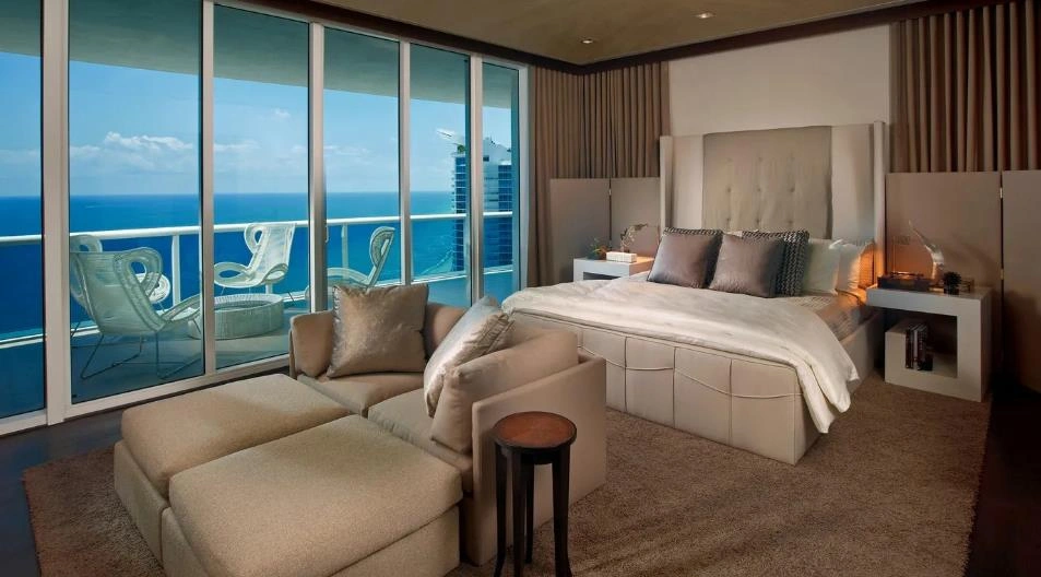 Women&rsquo;s relaxation bedroom with beige sofa, sea-view windows, and soft rug.