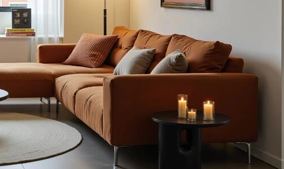 Candles of various sizes on a black side table in a small living room.