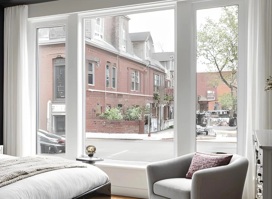 Large white-framed floor-to-ceiling windows in a modern small apartment bedroom.