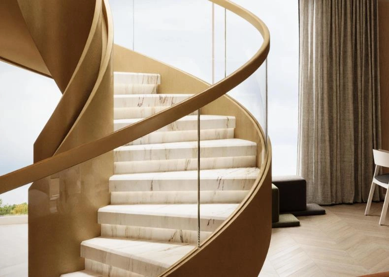 Gold-framed spiral staircase with marble steps in a loft apartment.