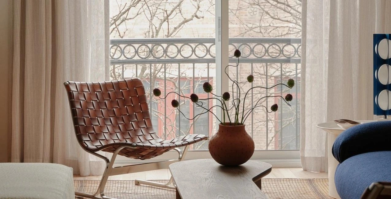 Brown leather woven chair placed by the window in a small apartment living room.